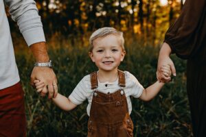 Little boy holding mom and dads hands during a photo session in Marietta, Ga.