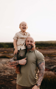 Dad holding son during family photos at sunset. 
