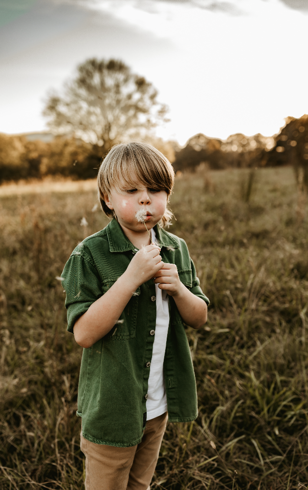 Little boy playing with flowers during a family photo session in Marietta, GA.